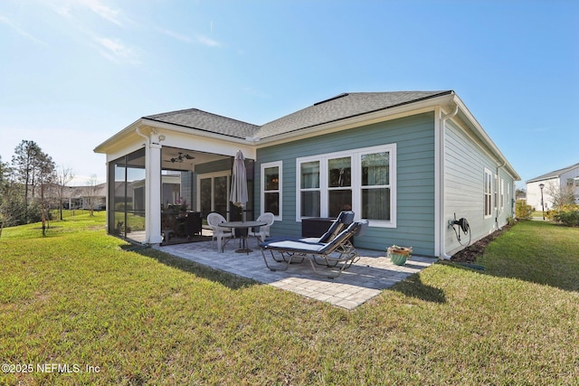 rear view of property with a shingled roof, a sunroom, a patio area, and a lawn