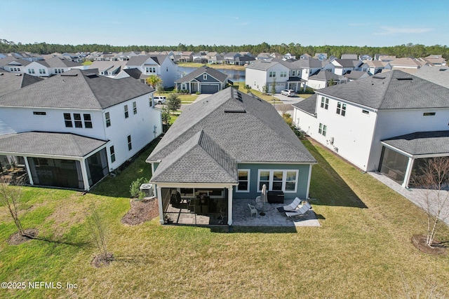 rear view of house featuring a sunroom, roof with shingles, a patio area, and a residential view