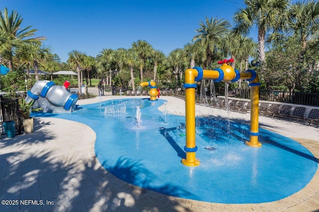 view of pool with playground community, fence, a water play area, and a water slide