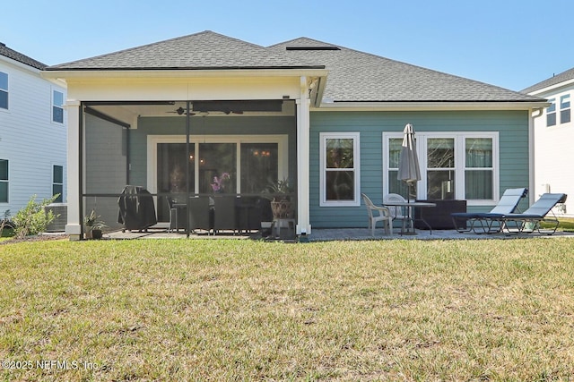 rear view of property with a yard, ceiling fan, a shingled roof, and a patio