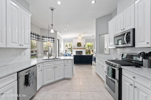 kitchen featuring light tile patterned floors, stainless steel appliances, white cabinetry, a sink, and a peninsula