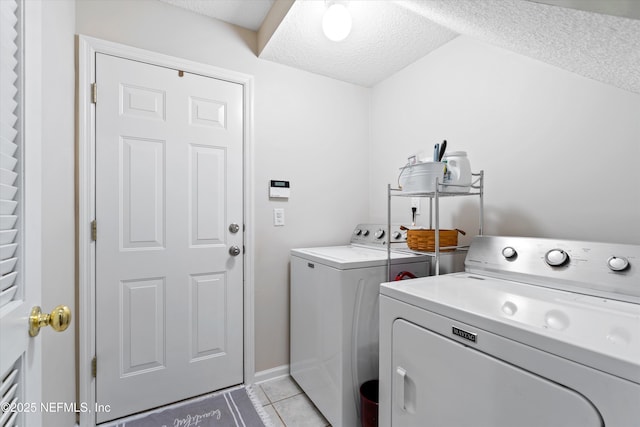 laundry area featuring laundry area, a textured ceiling, washing machine and clothes dryer, and light tile patterned floors