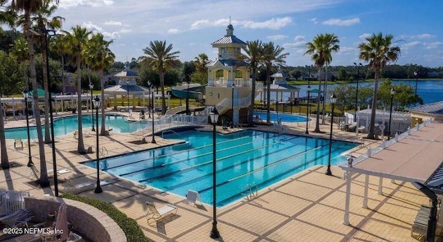 community pool with a water slide, a patio, and fence