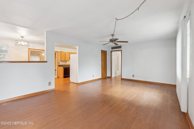 unfurnished living room with ceiling fan with notable chandelier, light wood finished floors, visible vents, and baseboards