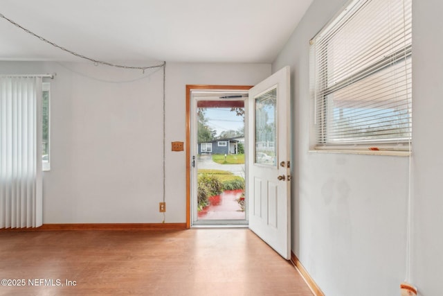 doorway with light wood-style floors and baseboards