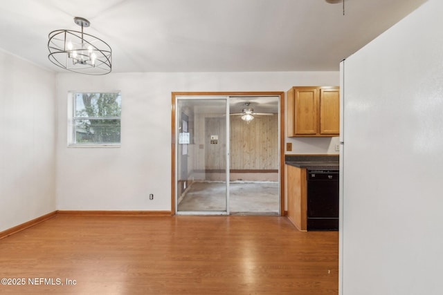 unfurnished dining area with light wood-type flooring, baseboards, and ceiling fan with notable chandelier