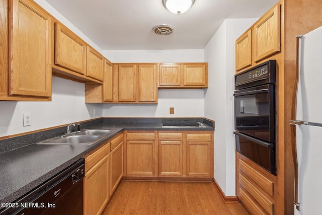 kitchen with dark countertops, visible vents, a sink, light wood-type flooring, and black appliances