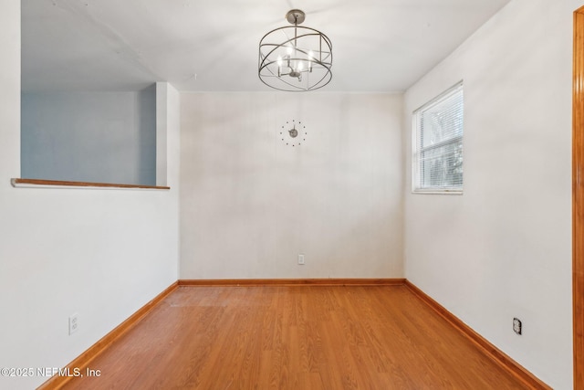 interior space with a chandelier, wood finished floors, and baseboards