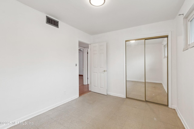 unfurnished bedroom with light floors, a closet, visible vents, and baseboards