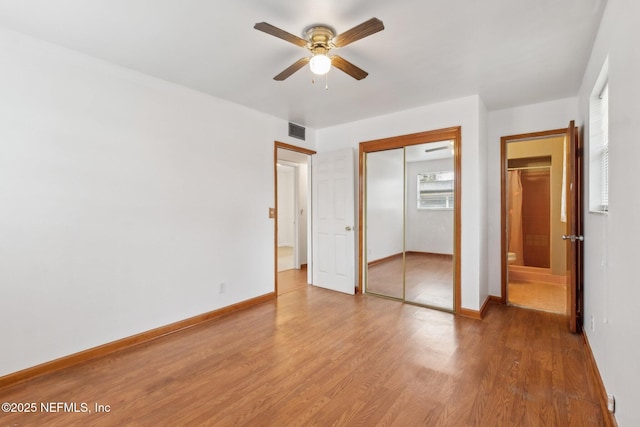 unfurnished bedroom featuring a closet, visible vents, baseboards, and wood finished floors