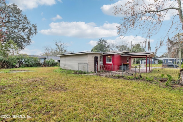 back of property with fence, a carport, and a yard