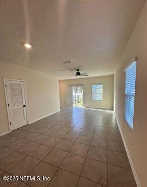 tiled spare room with ceiling fan, a textured ceiling, and baseboards