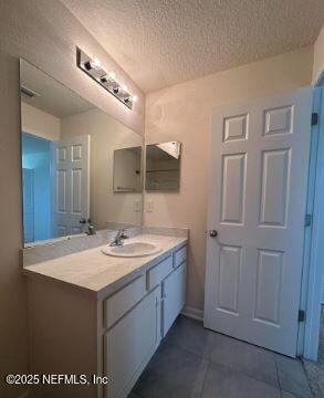 bathroom with tile patterned flooring, a textured ceiling, and vanity