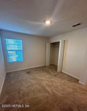 unfurnished bedroom featuring carpet, visible vents, a textured ceiling, and baseboards