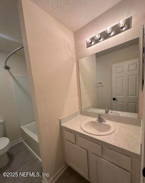 full bathroom featuring bathtub / shower combination, toilet, a textured ceiling, vanity, and baseboards