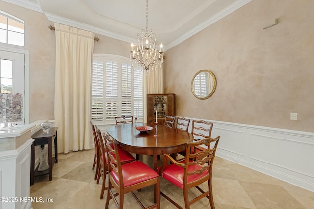 dining area with a wainscoted wall, a chandelier, a decorative wall, and crown molding