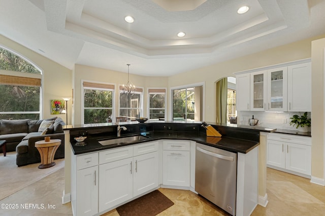 kitchen featuring a raised ceiling, stainless steel dishwasher, plenty of natural light, and a sink