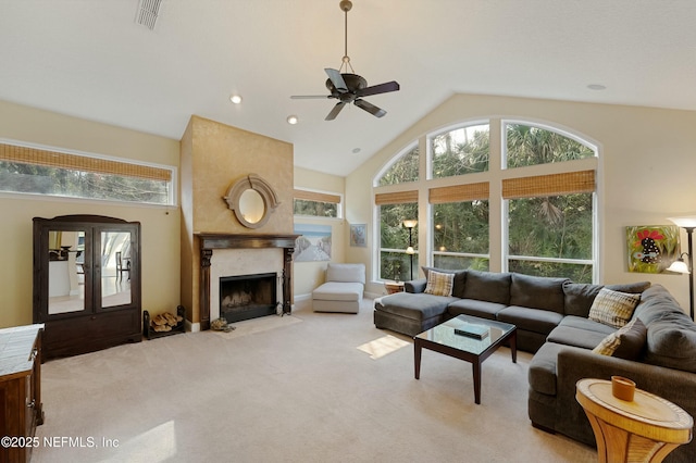 living room with visible vents, light colored carpet, a healthy amount of sunlight, high vaulted ceiling, and a high end fireplace