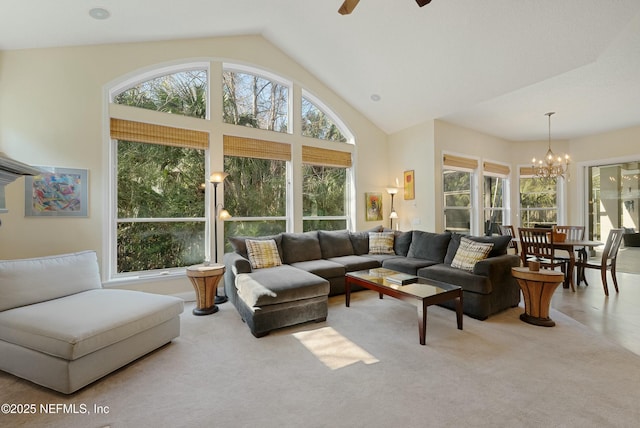 carpeted living room featuring ceiling fan with notable chandelier and high vaulted ceiling