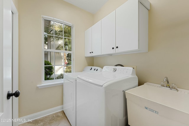 clothes washing area featuring cabinet space, a sink, baseboards, and separate washer and dryer