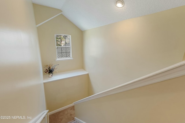 staircase with lofted ceiling, carpet, baseboards, and a textured ceiling