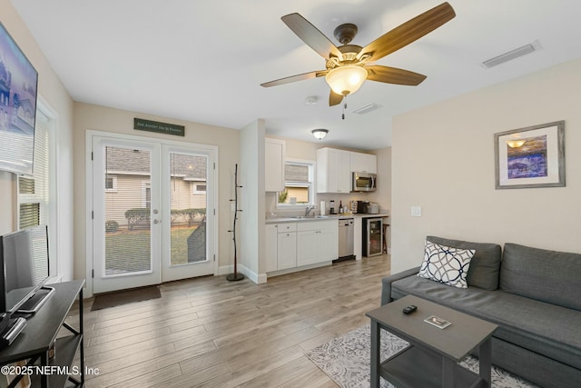 living room with light wood finished floors, wine cooler, visible vents, and a wealth of natural light