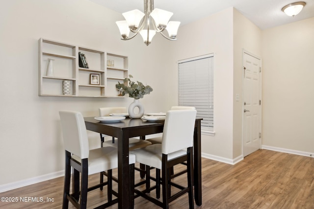 dining room with baseboards, a chandelier, and wood finished floors