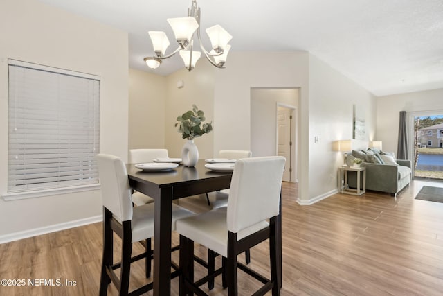 dining space featuring an inviting chandelier, baseboards, and wood finished floors