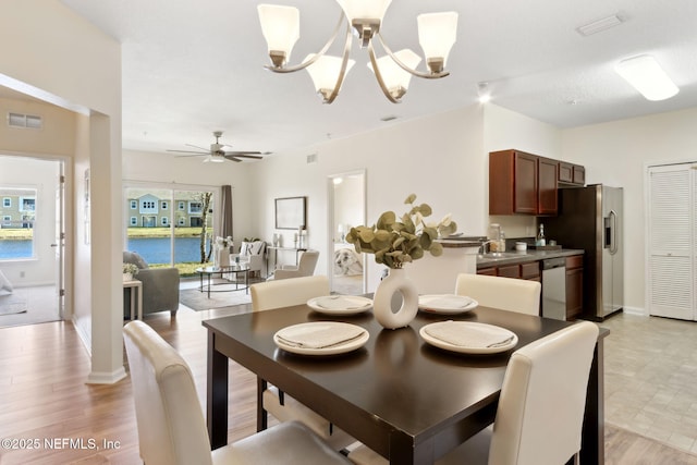 dining room featuring light wood-style flooring, visible vents, baseboards, and ceiling fan with notable chandelier