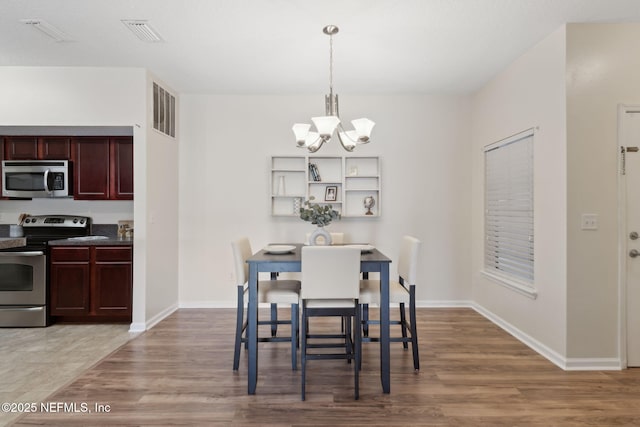 dining space with an inviting chandelier, baseboards, visible vents, and wood finished floors