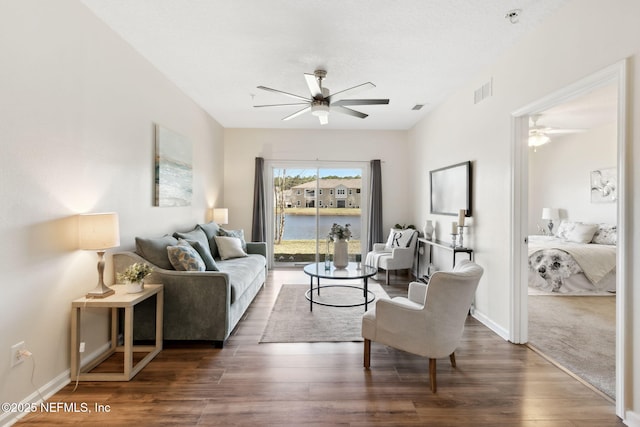 living room with visible vents, ceiling fan, baseboards, and wood finished floors