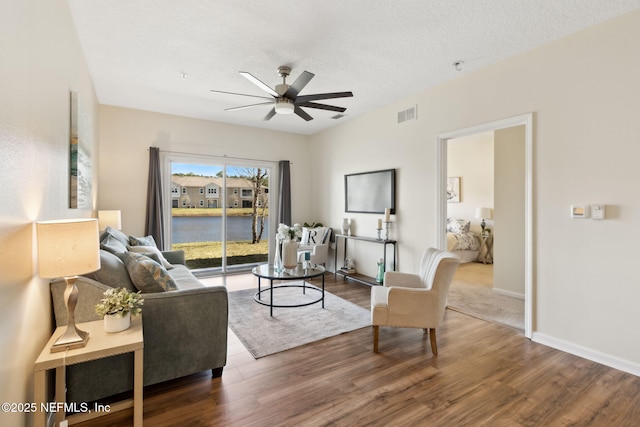 living area with a ceiling fan, baseboards, visible vents, and wood finished floors