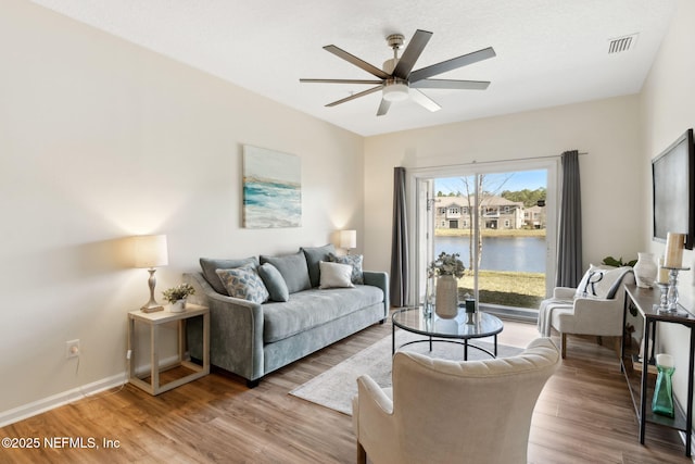 living area with visible vents, ceiling fan, baseboards, and wood finished floors