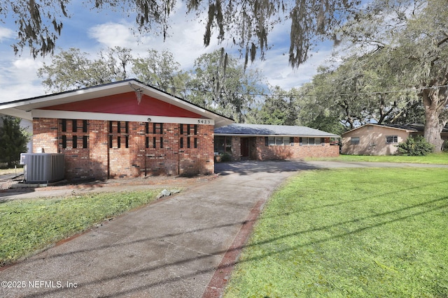 view of front of property featuring aphalt driveway, cooling unit, brick siding, and a front lawn