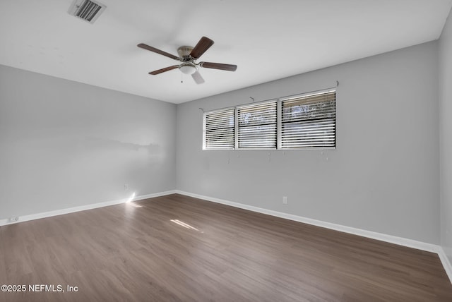 unfurnished room featuring dark wood-style floors, visible vents, ceiling fan, and baseboards