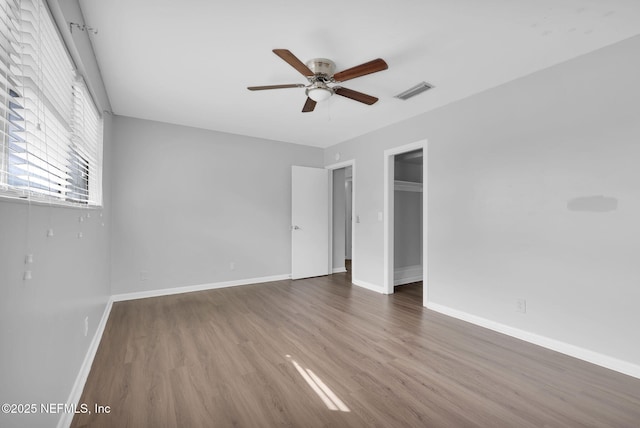 unfurnished bedroom featuring ceiling fan, baseboards, visible vents, and dark wood finished floors