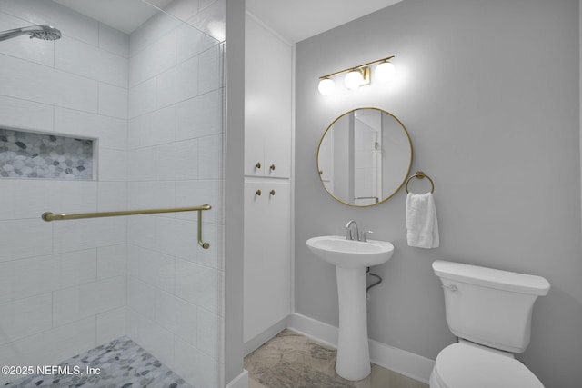 bathroom with toilet, marble finish floor, baseboards, and a sink