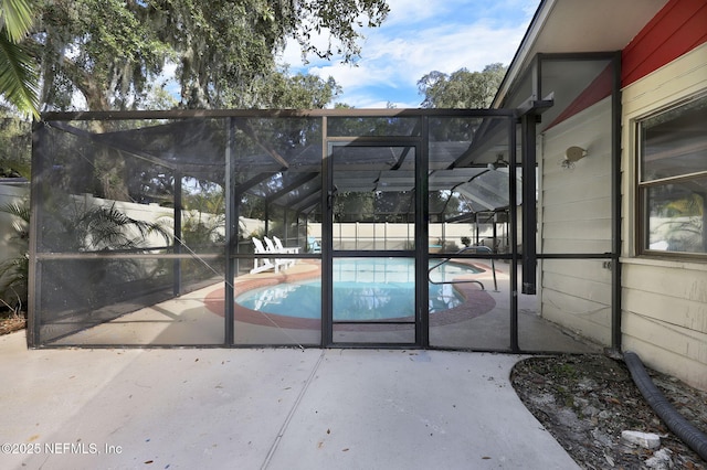 view of swimming pool with glass enclosure, fence, a fenced in pool, and a patio