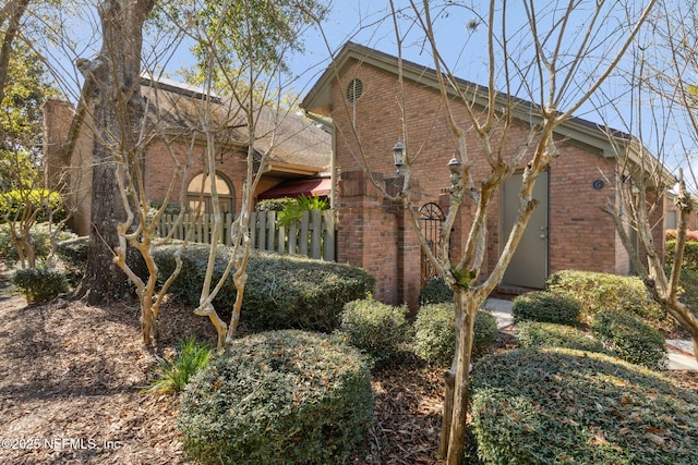 exterior space featuring brick siding and fence