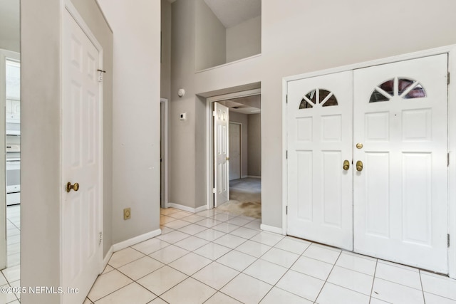 entrance foyer featuring light tile patterned floors, a high ceiling, and baseboards