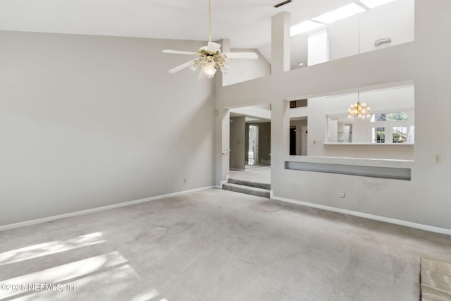 unfurnished living room with carpet, visible vents, high vaulted ceiling, baseboards, and ceiling fan with notable chandelier