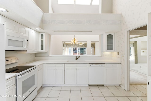 kitchen with white appliances, white cabinetry, glass insert cabinets, and light countertops