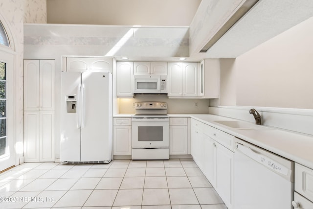 kitchen with light tile patterned floors, white appliances, a sink, white cabinetry, and light countertops