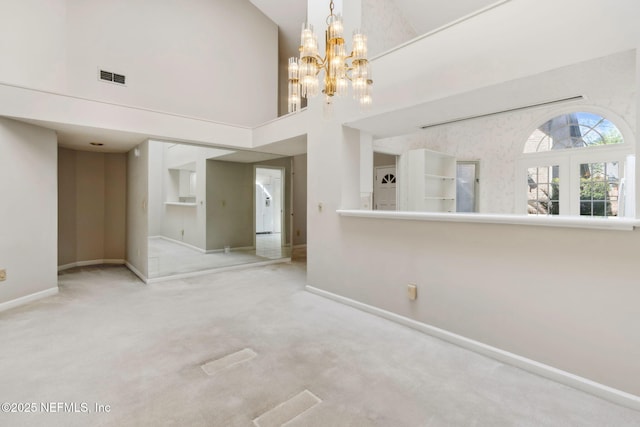 empty room featuring baseboards, visible vents, light colored carpet, a high ceiling, and a notable chandelier