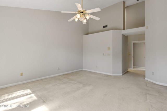 unfurnished room featuring visible vents, a high ceiling, light carpet, ceiling fan, and baseboards