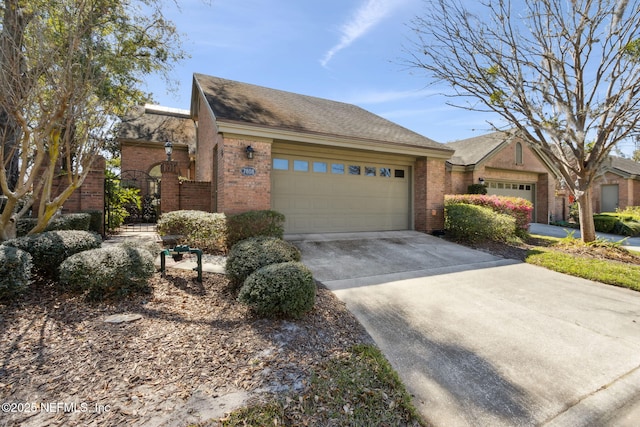 view of front of property with a garage, concrete driveway, brick siding, and a gate