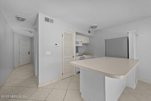 1255 Ponce Island Dr Unit C-733, Saint Augustine, FL 32084 - kitchen with light tile patterned flooring, white appliances, light countertops, a textured ceiling, and visible vents