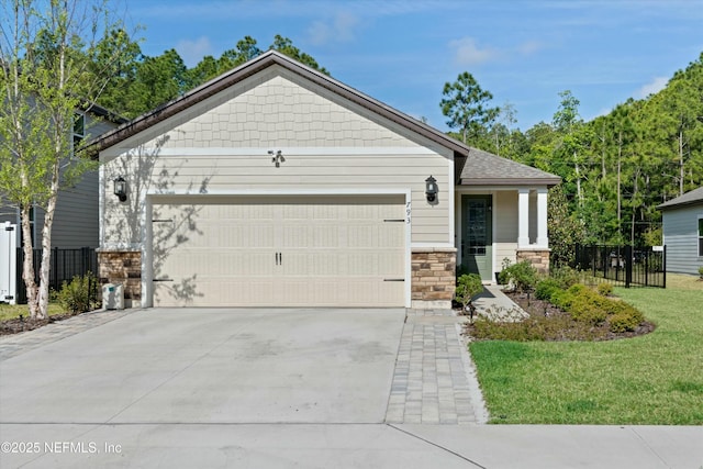 craftsman house featuring an attached garage, fence, stone siding, driveway, and a front lawn