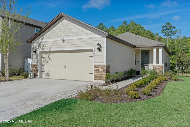 view of front of property featuring a garage, stone siding, driveway, roof with shingles, and a front yard