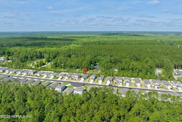 drone / aerial view featuring a wooded view and a residential view